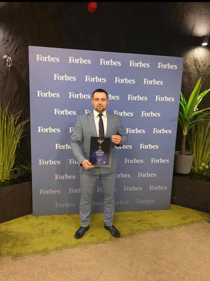 Businessman standing with Forbes Diamonds award for C2C sp. z o. o.
